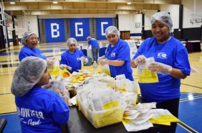 three women and two young girls pack meal bags
