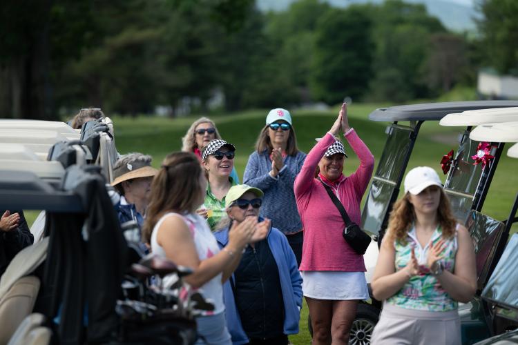 women golfers stand by golf carts cheering and clapping