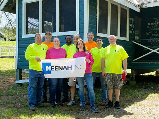 group from Neenah Inc with sign in front of cabin