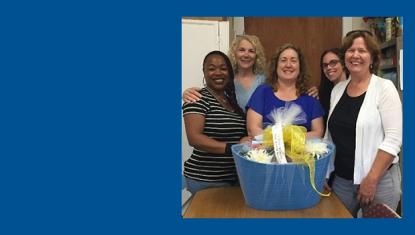 5 women stand with a gift basket